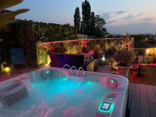 a hot tub on a patio at night at Spa de la Lune - Private love room suite with terrace and view - Air Conditioned- Double jacuzzi - Sauna - King size bed - Free WIFI - Free parking - Free breakfast - Close to CDG airport and to the North of Paris in Clichy-sous-Bois