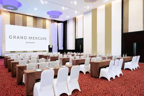 a large room with tables and white chairs and a screen at Grand Mercure Danang in Da Nang