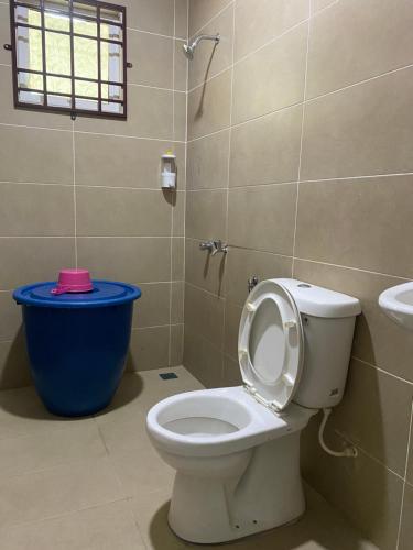 a bathroom with a toilet and a blue trash can at Ladiya Homestay Islamic 