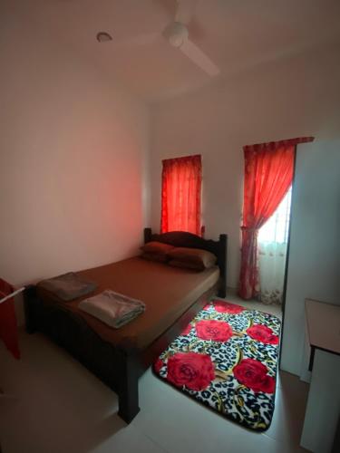 a bedroom with a bed and a window with red curtains at Ladiya Homestay Islamic 