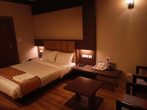a hotel room with a bed and a desk with a phone at Golden Peaks Hotel & Restaurant in Kalimpong