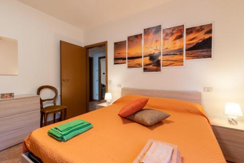 カポローナにあるCasaentinoのベッドルーム1室(壁に4つの絵画が飾られたオレンジ色のベッド1台付)