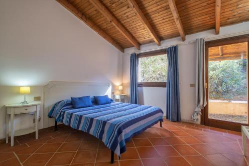 sypialnia z łóżkiem z niebieską pościelą i oknem w obiekcie Villa Dalia w mieście Stintino