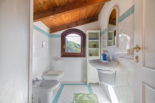 łazienka z 2 toaletami, umywalką i oknem w obiekcie Villa Dalia w mieście Stintino