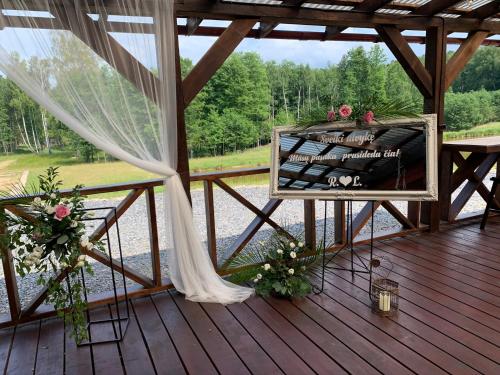 a porch with a table with wine bottles and flowers at Auksinio elnio slėnis in Rukliai
