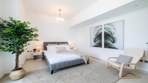 a bedroom with a bed and a chair and a plant at Hashtag Holiday Home - Luxury 2BDR Apartment on The Palm Azure Residences in Dubai