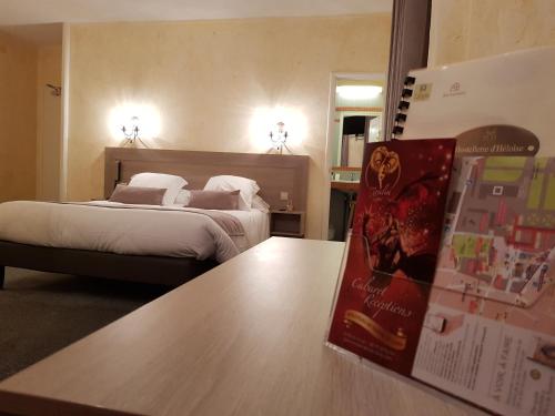 a hotel room with a bed and a book on a table at Hostellerie d'Héloïse Logis in Cluny