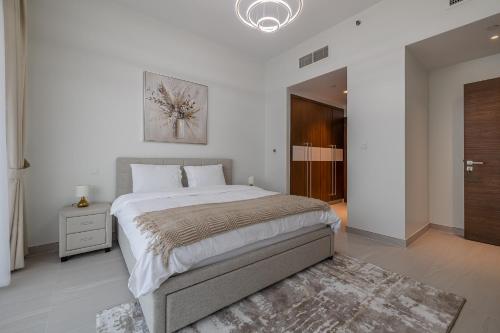 a white bedroom with a large bed and a rug at Close To Metro with Frame View in Dubai