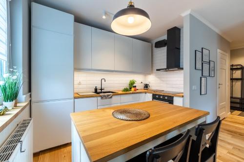 a kitchen with white cabinets and a wooden table at Komfortowy apartament z parkingiem in Wrocław