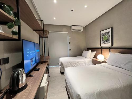 a hotel room with two beds and a flat screen tv at Acro Residences in Guiguinto