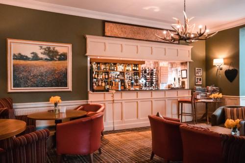 a restaurant with tables and chairs and a bar at The Pheasant Hotel, Holt, Norfolk - The Coaching Inn Group in Kelling
