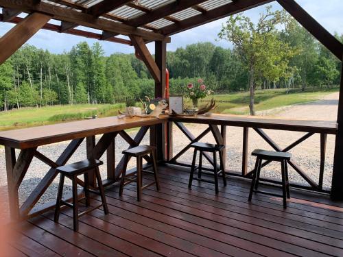 a large wooden table on a deck with stools at Auksinio elnio slėnis in Rukliai