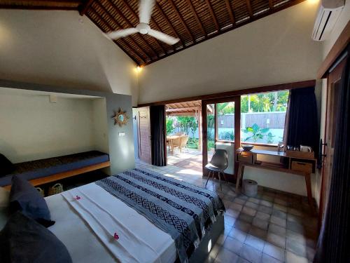 a bedroom with a bed and a desk and windows at Villa Saia in Gili Air
