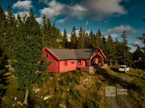 a red house with a black roof in the woods at Large Cottage 2 Baths and Sauna in Sjusjøen in Lillehammer