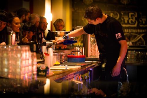 a man in a red shirt is pouring some drinks at PLUS Berlin Hostel und Hotel in Berlin