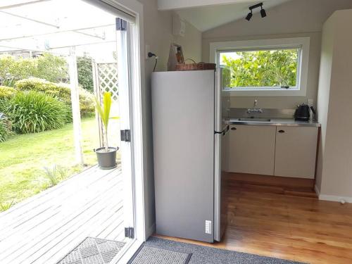 an open door to a kitchen with a refrigerator at Beach Break Cabin - short walk to beach and cafes in Waihi Beach