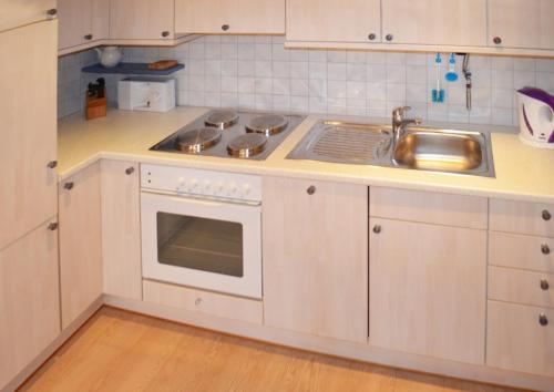 a white kitchen with a sink and a stove at Ferienwohnung Nebenan in Ebern