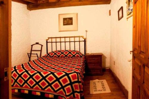 um quarto com uma cama com um cobertor vermelho e preto em Casa Tía Modesta es una cálida y acogedora casa rural em Cabezas Bajas