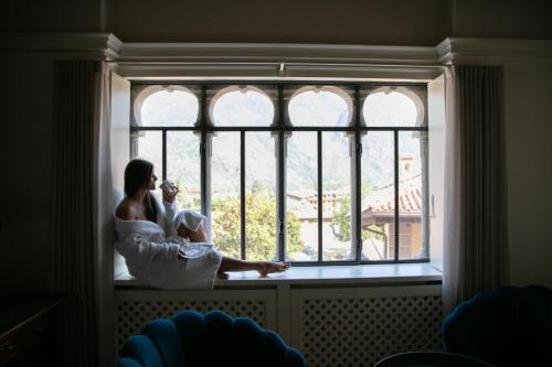 uma mulher sentada numa janela com um bebé em La Portineria Luxury B&B em Piancogno