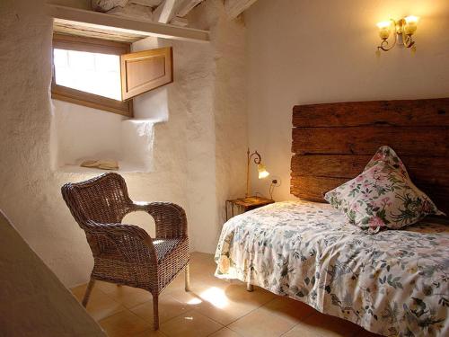 a bedroom with a bed and a chair and a window at Ca l'Agnès in Montseny