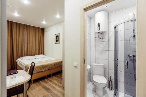 a bathroom with a toilet and a shower and a bed at Tourist Inn in Petrozavodsk