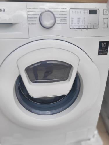 a white washing machine with a remote control on it at Maya Guest House - German Colony & Baháí Gardens, Haifa in Haifa