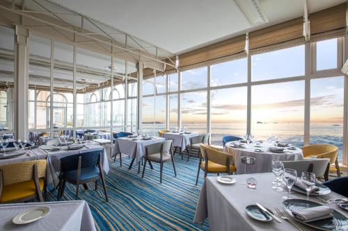 un restaurante con mesas, sillas y ventanas grandes en Grand Hôtel Des Thermes en Saint-Malo