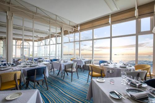 - un restaurant avec des tables, des chaises et de grandes fenêtres dans l'établissement Grand Hôtel Des Thermes, à Saint-Malo