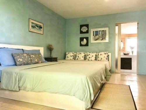 een slaapkamer met een groot bed met blauwe muren bij Chalianglom Resort Kohlarn in Ko Larn