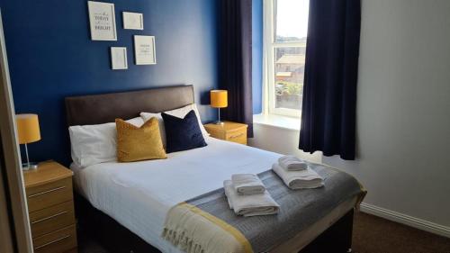 a blue bedroom with a bed with towels on it at The Davron Hotel in Fraserburgh
