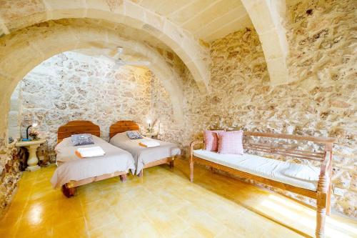 um quarto com 2 camas e uma parede de pedra em Gawhra Holiday Home em Xaghra
