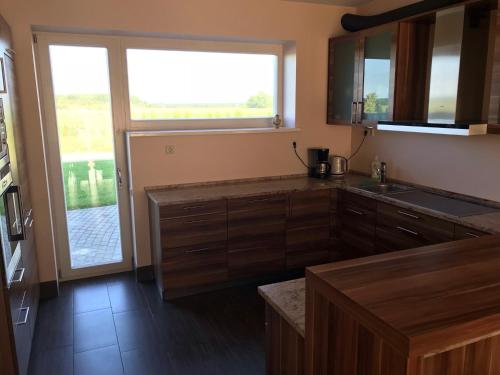 a kitchen with wooden cabinets and a large window at Beach Guesthouse Lenkas in Saraiķi