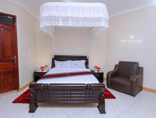a bedroom with a bed and a chair at Mbale Rosewood Hotel in Mbale