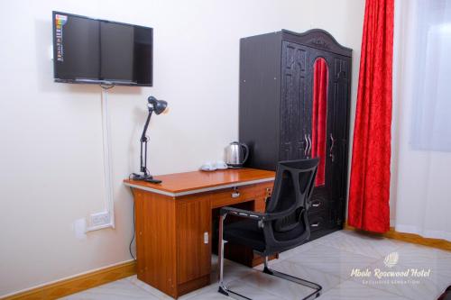 a desk with a television and a chair in a room at Mbale Rosewood Hotel in Mbale