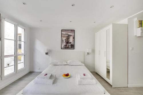 a white bedroom with a bed with a bowl of fruit on it at CMG - Cosy studio Le Marais in Paris