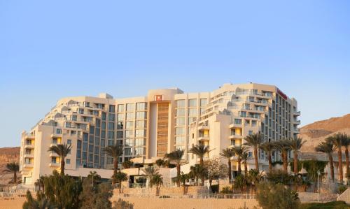 un grand bâtiment avec des palmiers devant lui dans l'établissement Leonardo Plaza Hotel Dead Sea, à Ein Bokek