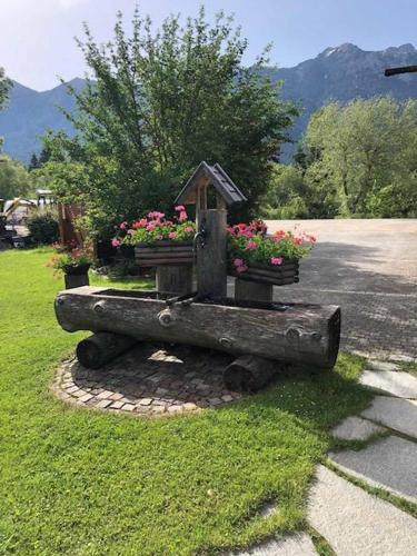 a bird feeder on a log with flowers in it at Landhaus Geierstanger in Wallgau
