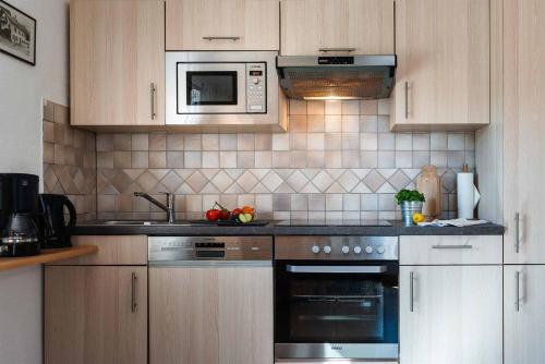 a kitchen with a stove and a microwave at Landhaus Geierstanger in Wallgau
