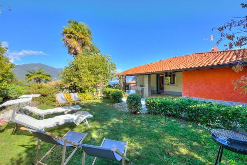 einen Garten mit Stühlen, einem Tisch und einem Haus in der Unterkunft Casa Francesca Garden And View - Happy Rentals in Castelveccana