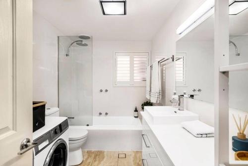 a white bathroom with a sink and a washing machine at Cute as a Button - Picket Fence 3 Bed Stylish Home in Unley