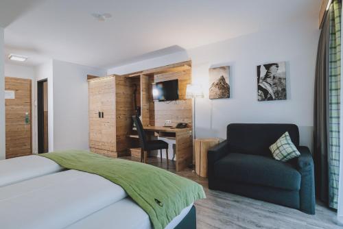 a bedroom with a bed and a chair and a desk at Der Gollinger in Saalbach Hinterglemm