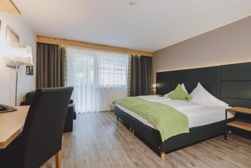 a hotel room with a large bed and a desk at Der Gollinger in Saalbach Hinterglemm