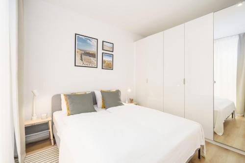 Dormitorio blanco con cama blanca y espejo en Apartament BIRCH TREE SurfingBird Dźwirzyno en Dźwirzyno
