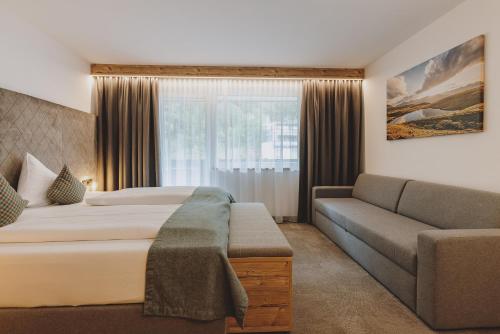 a hotel room with a bed and a couch at Der Gollinger in Saalbach Hinterglemm