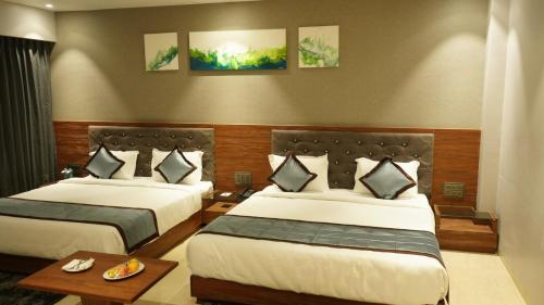 a hotel room with two beds and a table at Alaukik Hotel in Shirdi