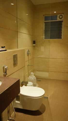 a bathroom with a toilet and a glass shower at Alaukik Hotel in Shirdi