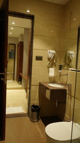 a bathroom with a toilet and a sink at Alaukik Hotel in Shirdi