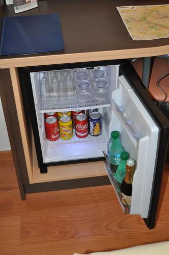 an open refrigerator with drinks and soda in a desk at Logis Hotel au tambour in Reims