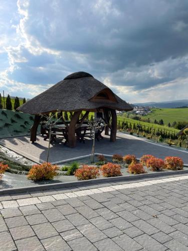 a pavilion with a table and some flowers at Domki Sówka in Dursztyn
