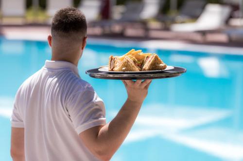 a man is holding a plate of food at Hotel Du Lac Congress Center & Spa in Ioannina